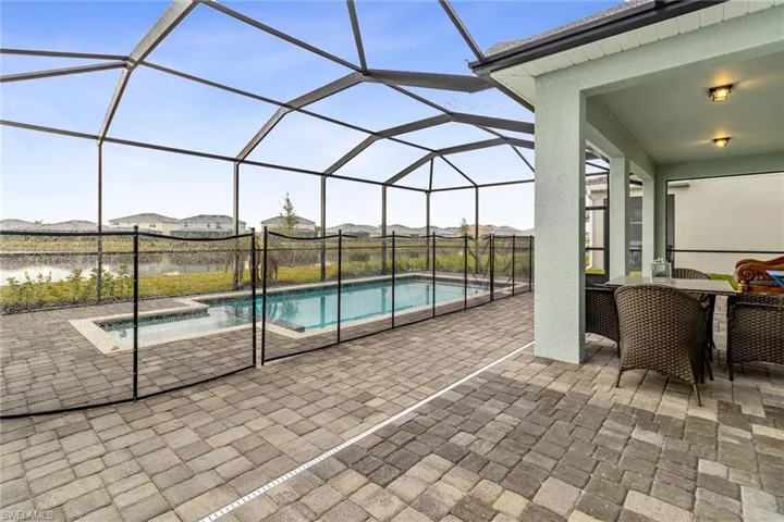 Screened-in outdoor living space featuring a paver patio, covered lanai, a rectangular swimming pool, and an integrated spa