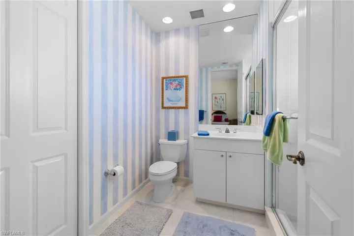 Full bathroom featuring wallpapered walls, vanity, light tile patterned floors, recessed lighting, and a shower