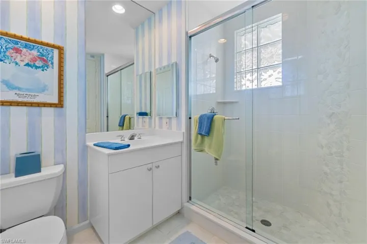 Full bathroom featuring wallpapered walls, vanity, a stall shower, light tile patterned floors, and recessed lighting