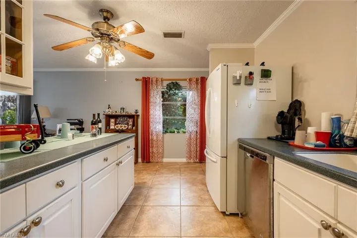 Kitchen featuring white cabinets, a healthy amount of sunlight, stainless steel dishwasher, and light tile patterned flooring