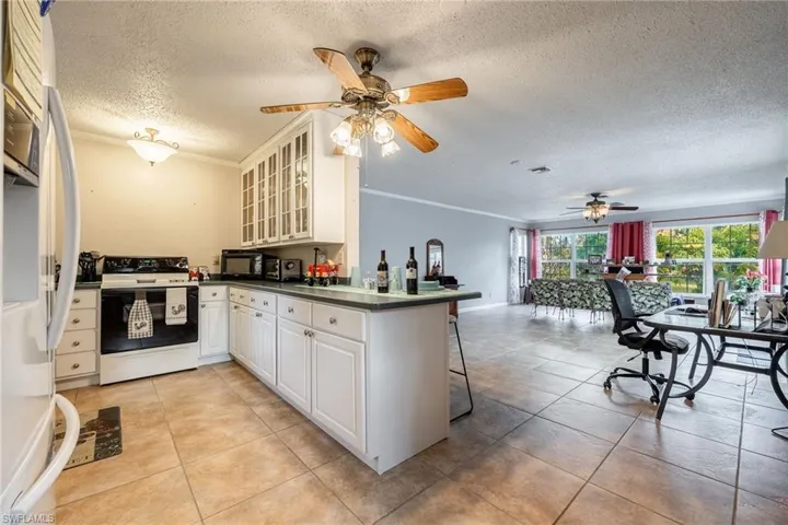 Kitchen featuring kitchen peninsula, crown molding, white cabinets, and white appliances