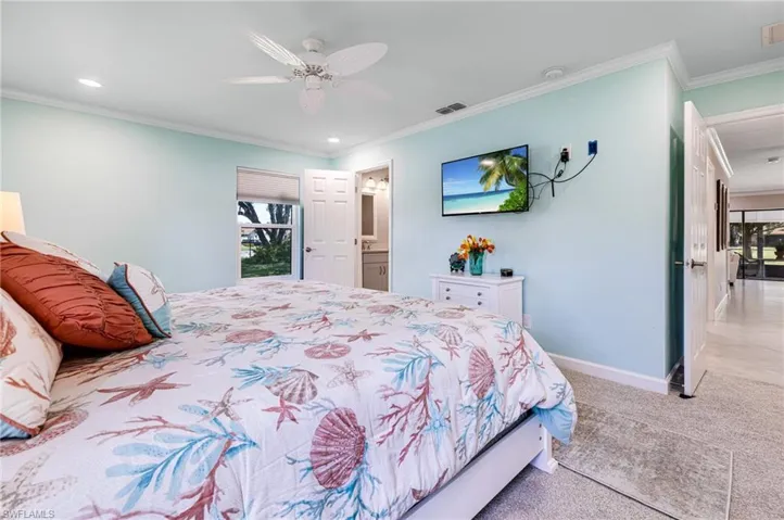 Carpeted bedroom featuring ceiling fan, crown molding, and connected bathroom