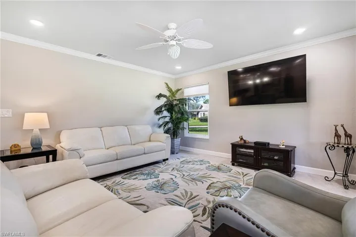 Living room featuring ornamental molding, light carpet, and ceiling fan