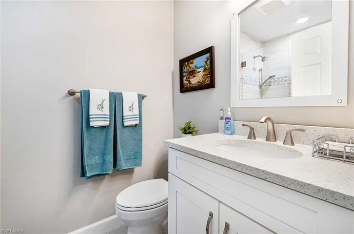 Bathroom with tiled shower, toilet, and vanity