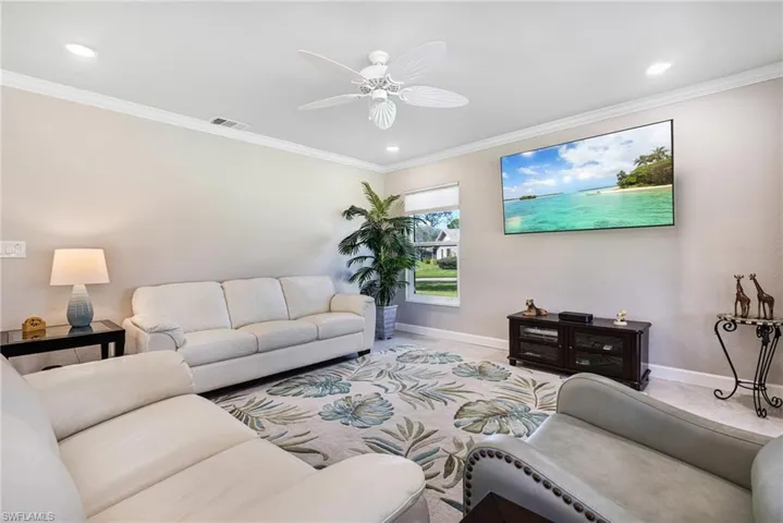 Living room with ornamental molding, light colored carpet, and ceiling fan