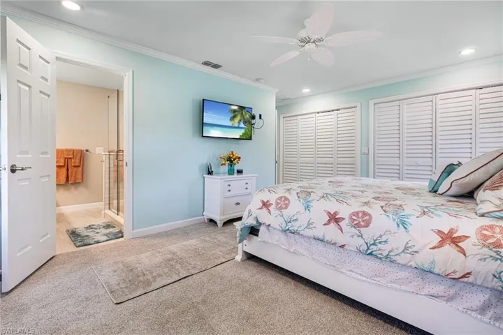 Bedroom with ceiling fan, connected bathroom, carpet flooring, and ornamental molding