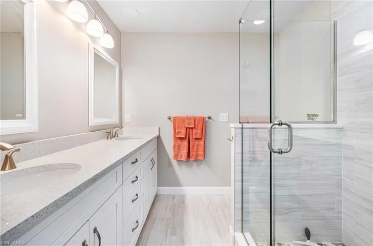 Bathroom featuring tile floor with a vanity, and a shower with shower door