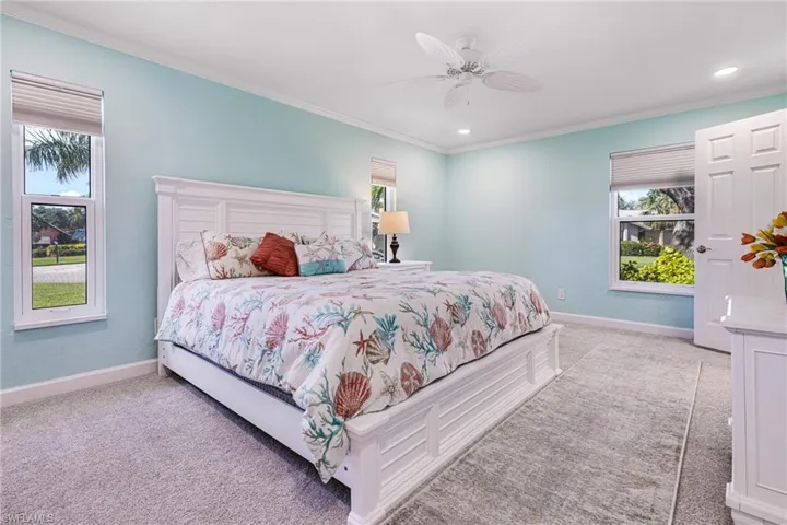 Bedroom with ornamental molding, light carpet, and ceiling fan
