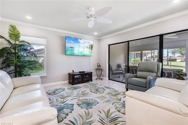 Living room with ornamental molding, a wealth of natural light, and ceiling fan