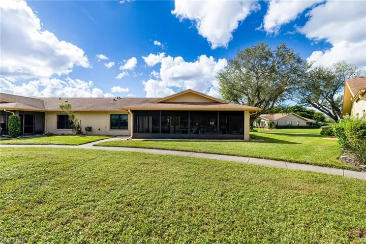 Back of property with a sunroom and a yard
