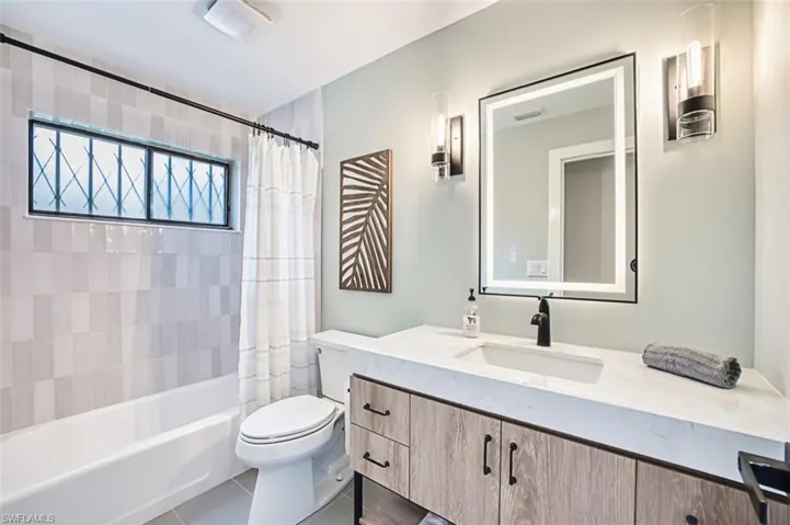 Full bath featuring vanity, toilet, and shower / bathtub combination with curtain