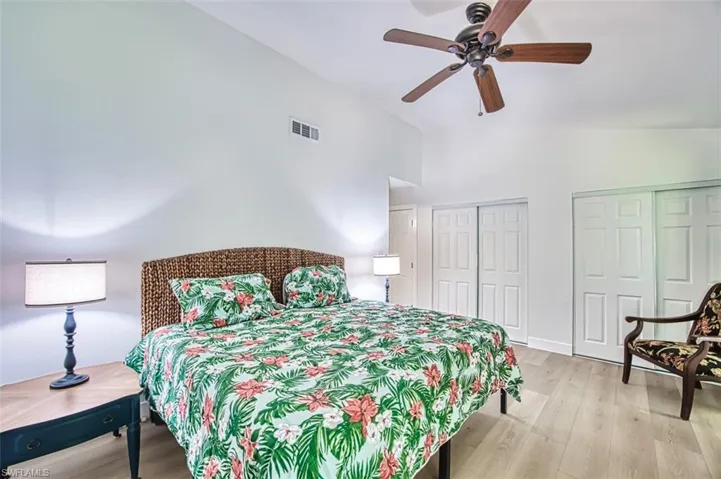 Bedroom featuring vaulted ceiling, two closets, light wood-style floors, and a ceiling fan