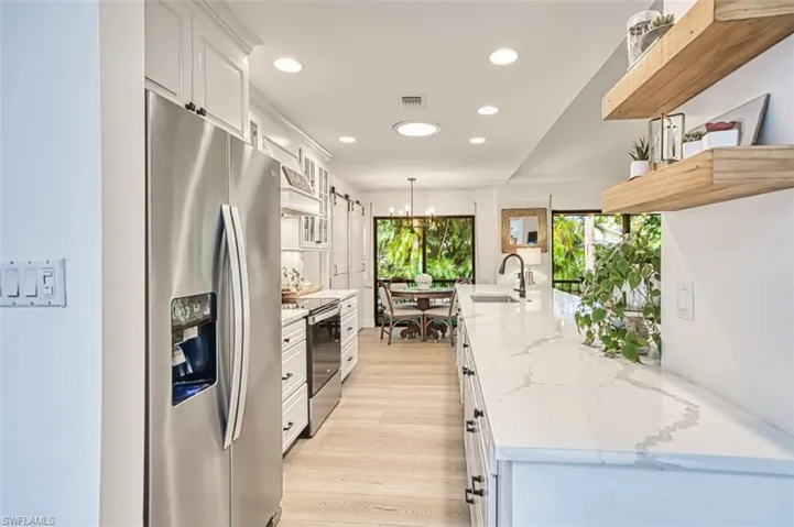 Kitchen featuring stainless steel appliances, recessed lighting, premium range hood, white cabinetry, and light wood-style floors
