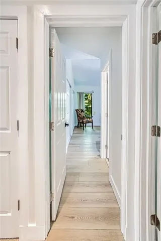 Hallway featuring lofted ceiling, light wood-style floors, and baseboards