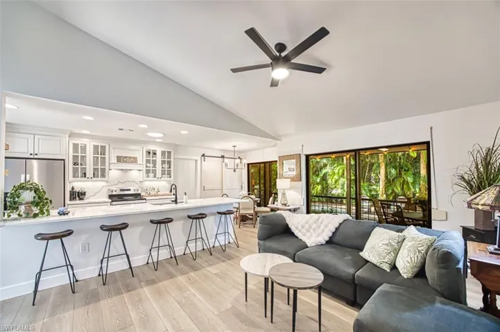Living area with a ceiling fan, recessed lighting, light wood-type flooring, and high vaulted ceiling