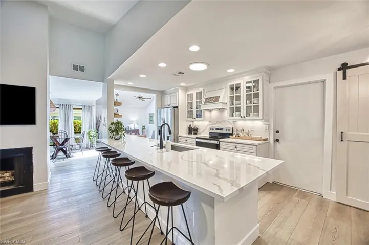 Kitchen with appliances with stainless steel finishes, a kitchen breakfast bar, light wood-type flooring, a sink, and white cabinetry