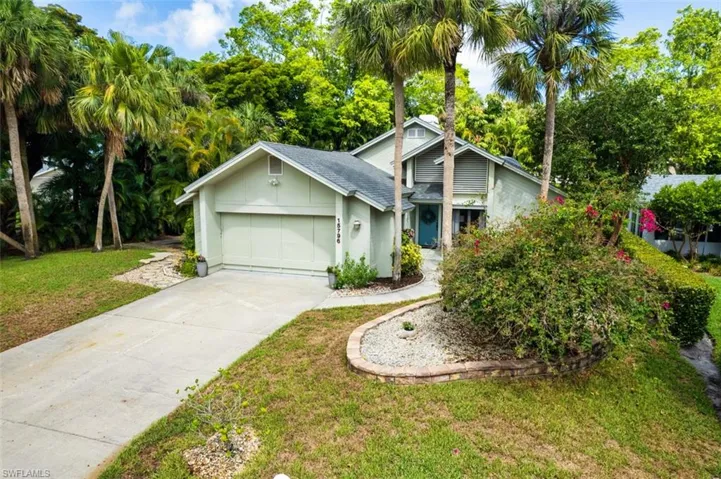 View of front of property with concrete driveway, a front yard, a garage, board and batten siding, and roof with shingles