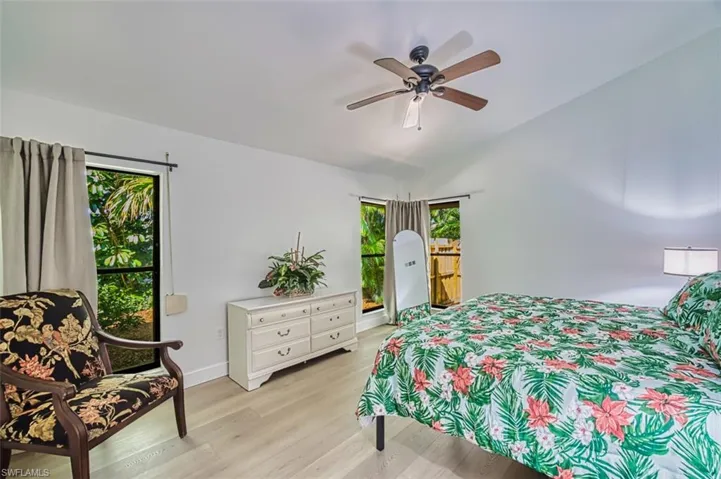 Bedroom with light wood-style floors, ceiling fan, vaulted ceiling, access to outside, and baseboards