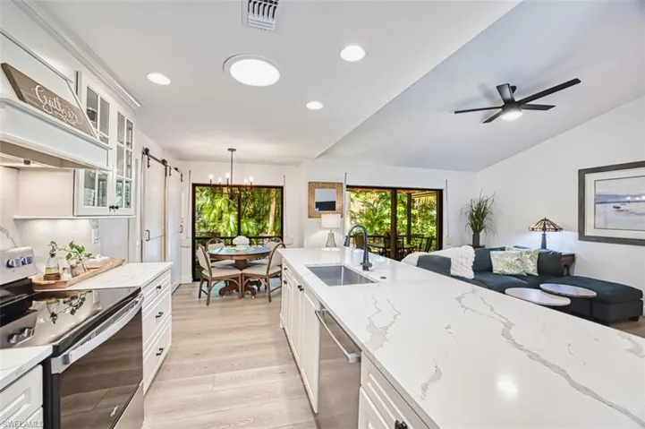 Kitchen featuring stainless steel appliances, a sink, a chandelier, light wood-style flooring, and white cabinetry