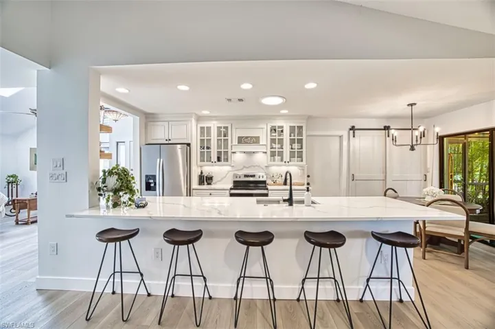 Kitchen with stainless steel appliances, a sink, light wood-style floors, a breakfast bar area, and recessed lighting