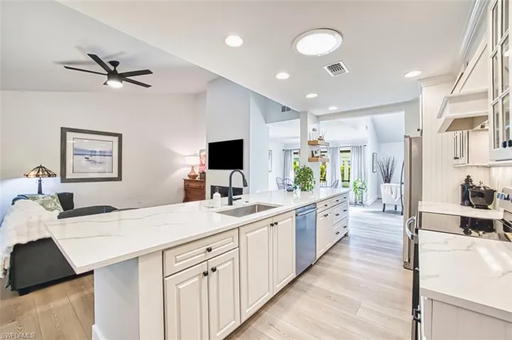 Kitchen featuring a sink, appliances with stainless steel finishes, open floor plan, light wood-style floors, and white cabinetry