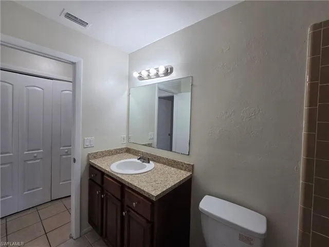 Bathroom with vanity, light tile patterned flooring, and a textured wall