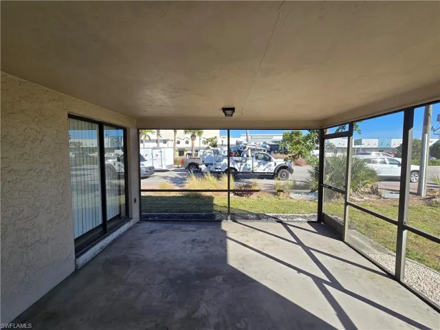 Unfurnished sunroom with a textured wall and unfinished concrete floors