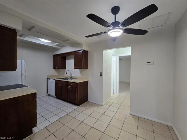 Kitchen with light countertops, light tile patterned flooring, dark brown cabinetry, white appliances, and ceiling fan