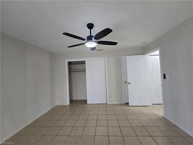 Unfurnished bedroom with ceiling fan, light tile patterned floors, and a closet