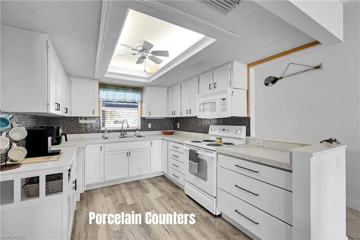 Porcelain countertops and tile backsplash dress up this white kitchen with tons of storage-lots of cabinets and soft close drawers.