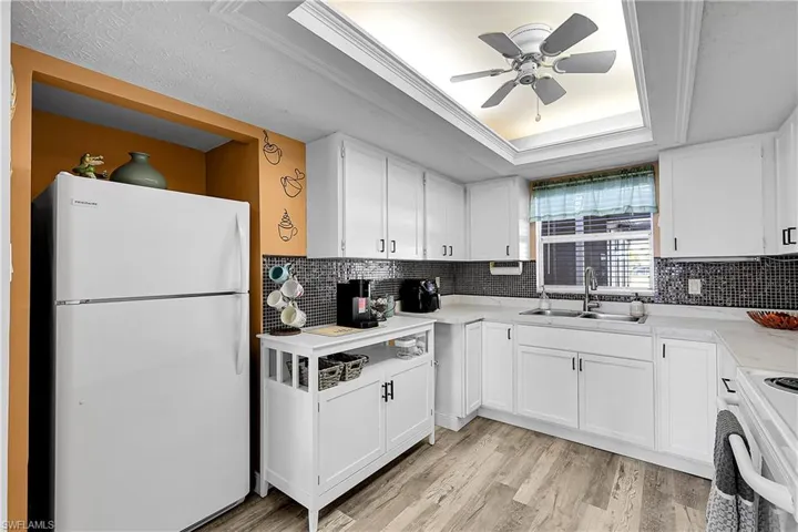 Porcelain countertops and tile backsplash dress up this white kitchen. Fan in tray ceiling keeps the kitchen cool.