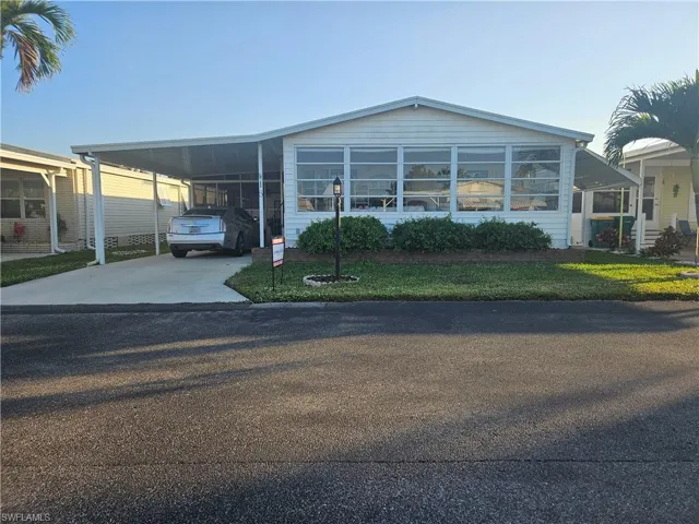 Manufactured / mobile home featuring a carport and a front lawn