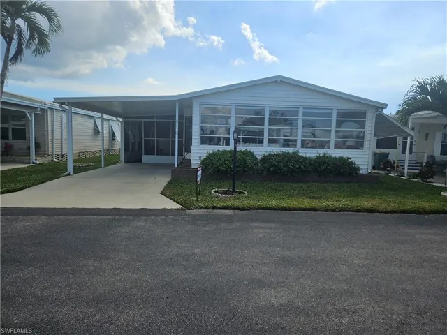 View of front of house with a front yard and a carport