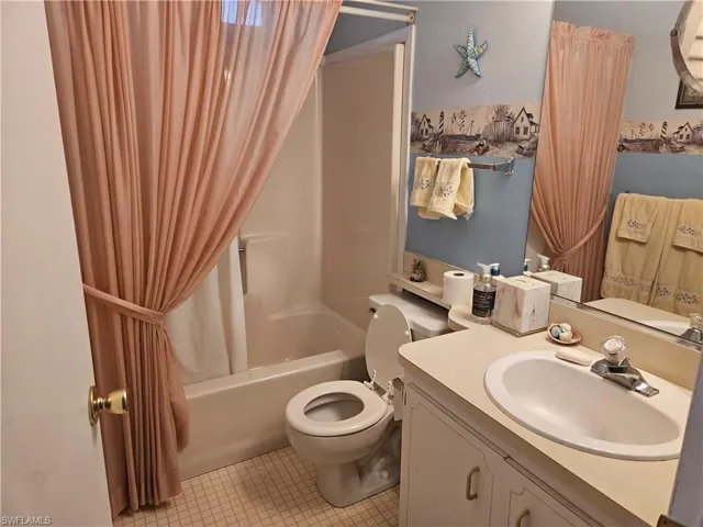 Full bathroom with tile patterned flooring, sink, shower / bath combination with curtain, and toilet