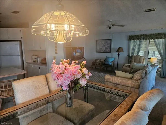 Carpeted living room featuring a chandelier and a textured ceiling