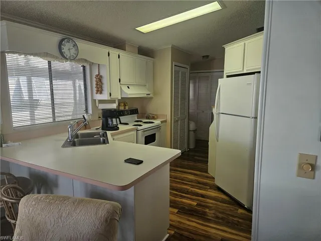 Kitchen with white appliances, a kitchen bar, kitchen peninsula, and sink