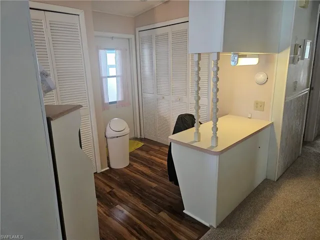 Kitchen with white cabinetry, dark wood-type flooring, ornamental molding, and kitchen peninsula