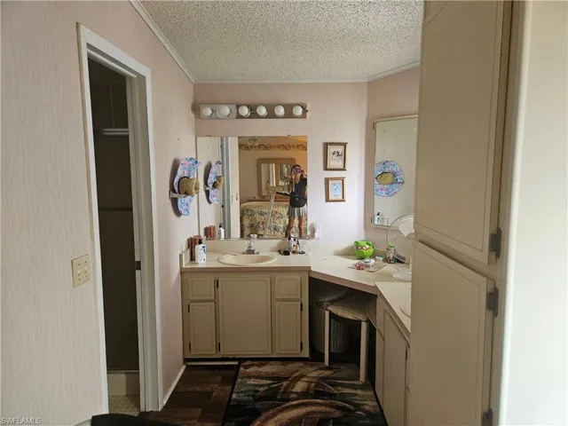 Bathroom with crown molding, vanity, and a textured ceiling