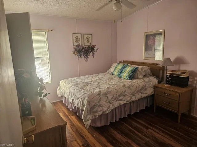 Bedroom with dark wood-type flooring, ceiling fan, and a textured ceiling