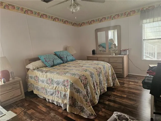 Bedroom with ceiling fan, dark hardwood / wood-style floors, and a textured ceiling