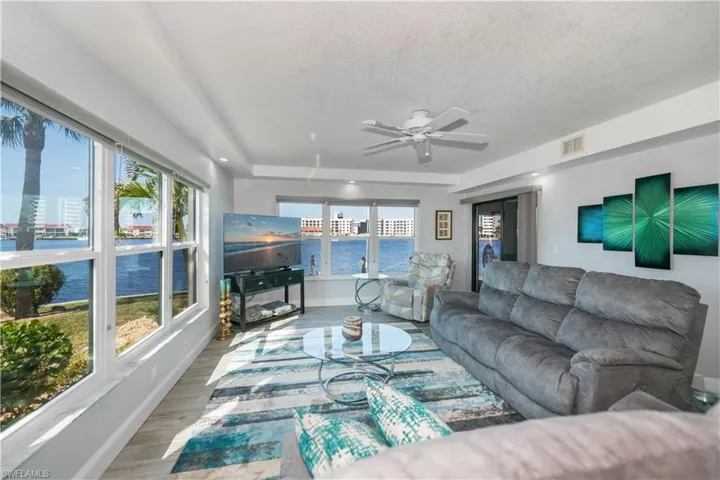 Living room with ceiling fan, a textured ceiling, and wood-type flooring