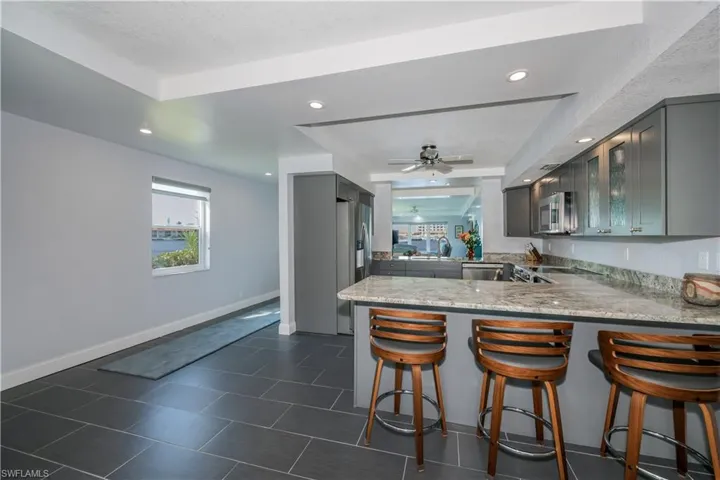 Kitchen featuring appliances with stainless steel finishes, ceiling fan, a raised ceiling, and kitchen peninsula