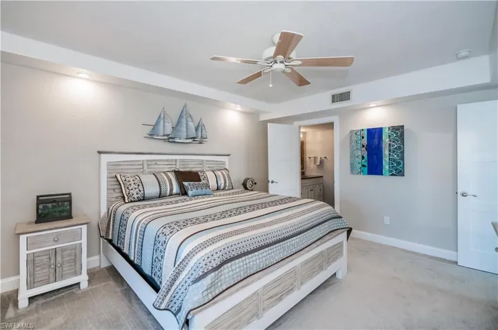 Carpeted bedroom with ceiling fan and ensuite bath