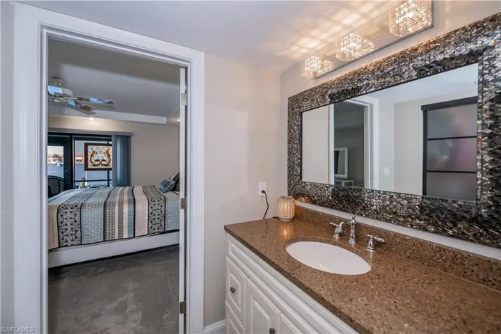 Bathroom with ceiling fan with notable chandelier and vanity