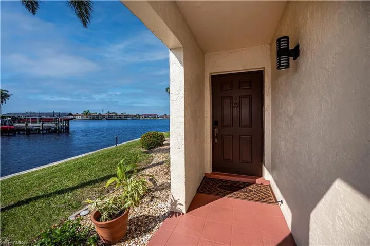 Entrance to property featuring a water view and a lawn