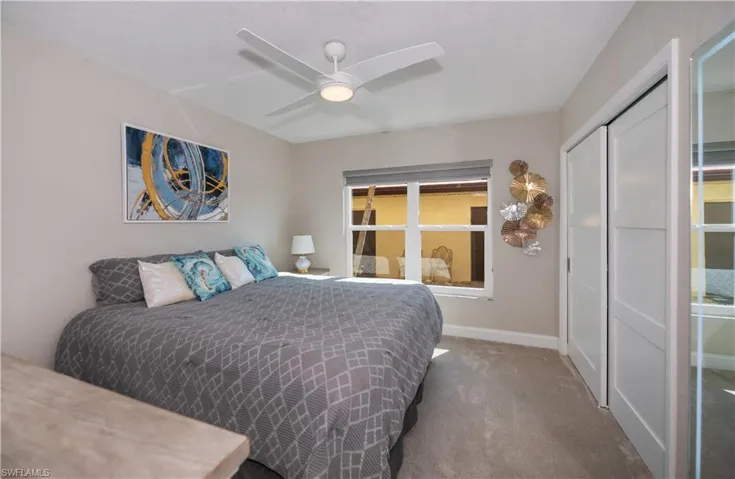 Carpeted bedroom featuring ceiling fan and a closet