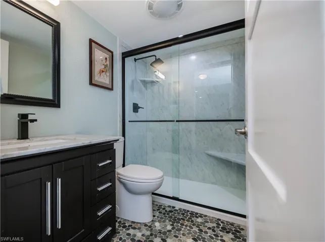 Bathroom with walk in shower, vanity, and toilet