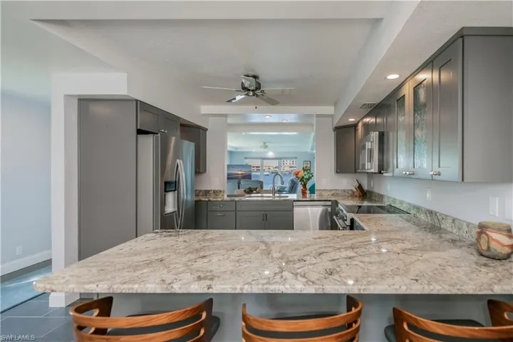 Kitchen featuring kitchen peninsula, stainless steel appliances, gray cabinetry, and a kitchen breakfast bar