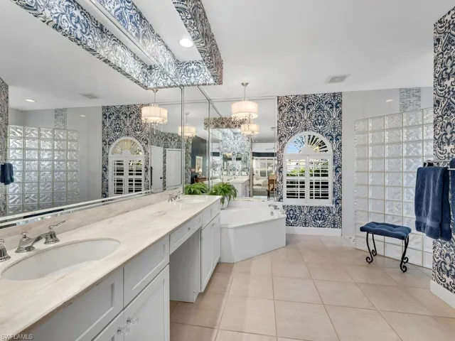 Bathroom with tile patterned flooring, vanity, a washtub, and tile walls