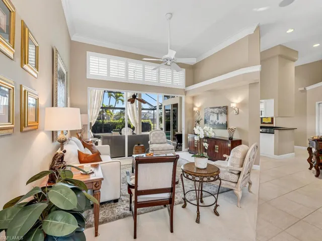 Living room featuring ceiling fan, a towering ceiling, ornamental molding, and light tile patterned flooring